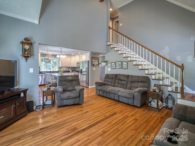 7376 NC-181 Hwy, Morganton, NC 28655 - living room with crown molding, stairs, light wood finished floors, a high ceiling, and a chandelier