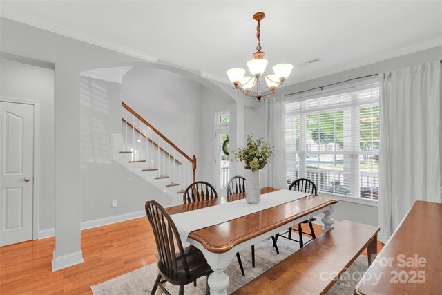 20234 Middletown Rd, Cornelius, NC 28031 - dining area with a chandelier, arched walkways, light wood-type flooring, stairway, and ornamental molding