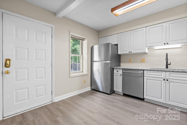 2705 N Center St Unit 76, Hickory, NC 28601 - kitchen with stainless steel appliances, beam ceiling, white cabinetry, light wood-style flooring, and light stone countertops