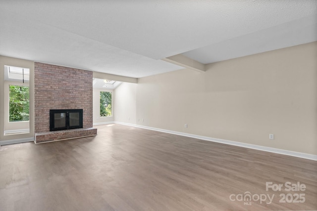 2705 N Center St Unit 76, Hickory, NC 28601 - unfurnished living room featuring wood finished floors, a fireplace, and beam ceiling