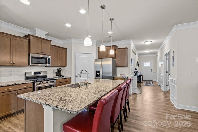 117 Cup Chase Dr, Mooresville, NC 28115 - kitchen featuring appliances with stainless steel finishes, ornamental molding, wood finished floors, a breakfast bar, and light stone countertops