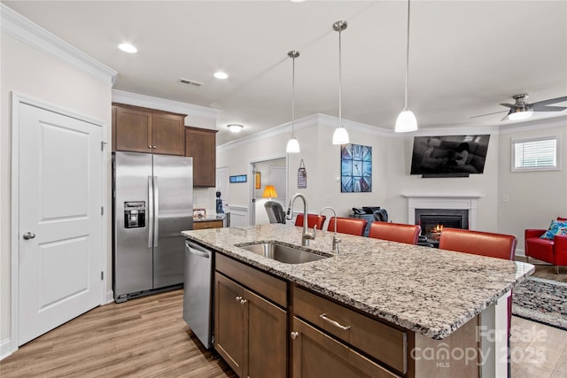 117 Cup Chase Dr, Mooresville, NC 28115 - kitchen with stainless steel appliances, ornamental molding, light wood finished floors, a lit fireplace, and open floor plan