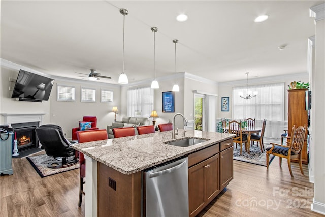 117 Cup Chase Dr, Mooresville, NC 28115 - kitchen featuring stainless steel dishwasher, light wood finished floors, a lit fireplace, a center island with sink, and hanging light fixtures