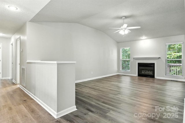 824 17th Avenue Dr SE, Hickory, NC 28602 - unfurnished living room with vaulted ceiling, ceiling fan, plenty of natural light, a glass covered fireplace, and wood finished floors