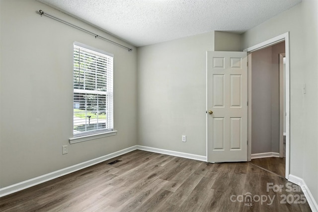824 17th Avenue Dr SE, Hickory, NC 28602 - unfurnished bedroom with wood finished floors, multiple windows, and a textured ceiling