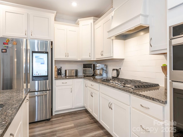 1711 Woodend Dr, Indian Trail, NC 28079 - kitchen featuring appliances with stainless steel finishes, premium range hood, white cabinets, backsplash, and ornamental molding