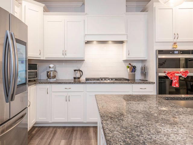 1711 Woodend Dr, Indian Trail, NC 28079 - kitchen featuring appliances with stainless steel finishes, white cabinetry, crown molding, dark stone countertops, and decorative backsplash