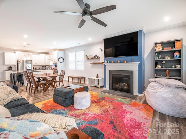 1711 Woodend Dr, Indian Trail, NC 28079 - living area with crown molding, a ceiling fan, wood finished floors, a glass covered fireplace, and recessed lighting