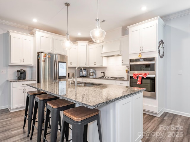 1711 Woodend Dr, Indian Trail, NC 28079 - kitchen with stainless steel appliances, premium range hood, wood finished floors, tasteful backsplash, and ornamental molding