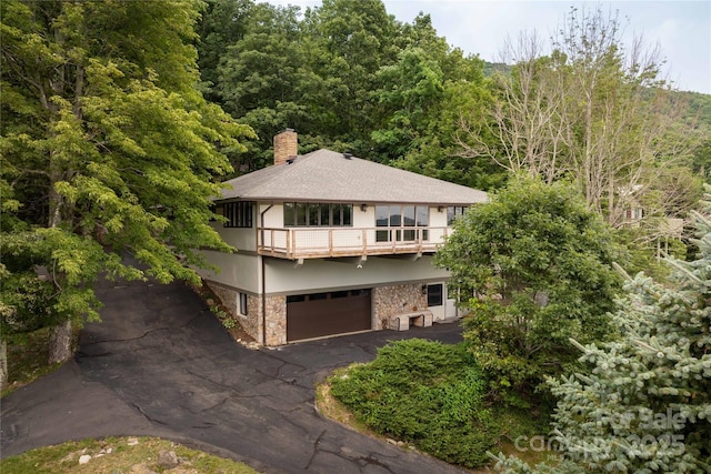 1648 Skyland Dr Unit 77, Seven Devils, NC 28604 - view of front of home with a balcony, stone siding, a chimney, a garage, and driveway