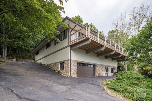 1648 Skyland Dr Unit 77, Seven Devils, NC 28604 - view of side of home with a garage, stone siding, a balcony, driveway, and stucco siding
