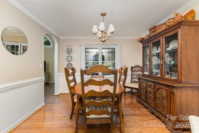 101 Citation Ln, Gastonia, NC 28056 - dining area with a chandelier, light wood-type flooring, a textured ceiling, ornamental molding, and arched walkways
