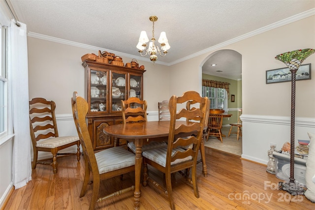 101 Citation Ln, Gastonia, NC 28056 - dining area featuring arched walkways, light wood-style floors, a chandelier, a textured ceiling, and crown molding