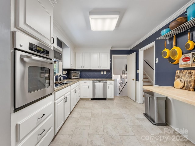 3200 Spring Valley Rd, Charlotte, NC 28210 - kitchen featuring appliances with stainless steel finishes, white cabinetry, ornamental molding, tasteful backsplash, and light stone countertops