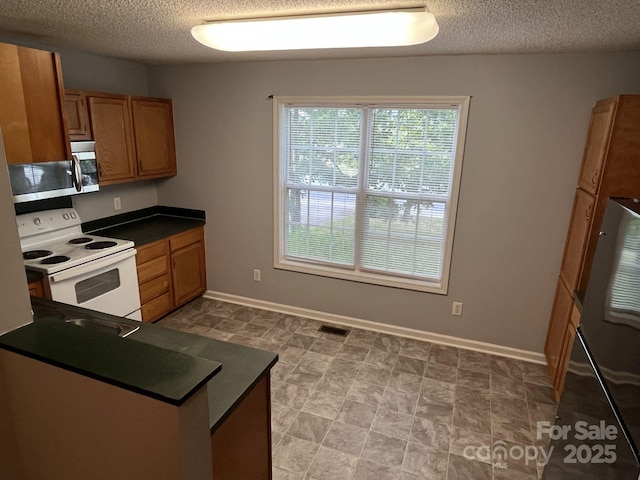 1015 Piney Church Rd, Concord, NC 28025 - kitchen with appliances with stainless steel finishes, dark countertops, a textured ceiling, and brown cabinets
