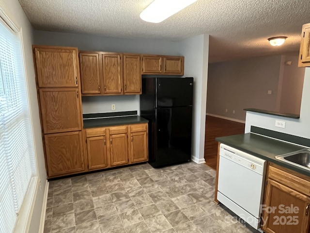 1015 Piney Church Rd, Concord, NC 28025 - kitchen featuring freestanding refrigerator, dishwasher, dark countertops, brown cabinets, and a textured ceiling