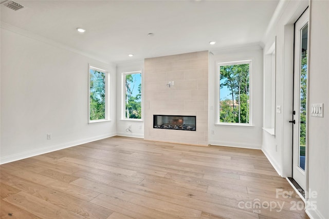 9511 Coast Laurel Ave NW, Concord, NC 28027 - unfurnished living room with light wood-style floors, a tile fireplace, ornamental molding, and recessed lighting