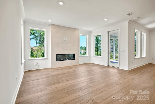 9511 Coast Laurel Ave NW, Concord, NC 28027 - unfurnished living room featuring healthy amount of natural light, hardwood / wood-style floors, a tile fireplace, recessed lighting, and crown molding