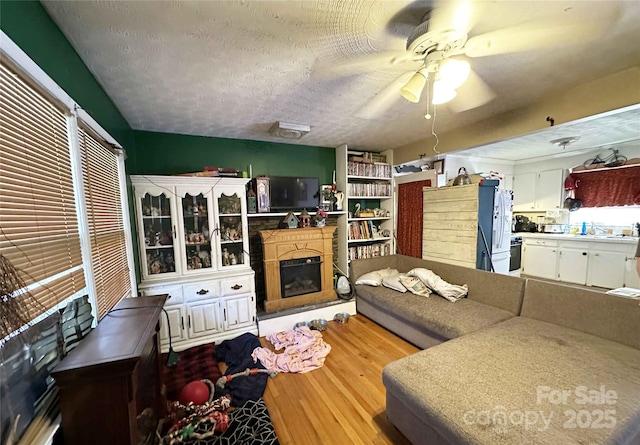 502 Monroe St, Shelby, NC 28150 - living room featuring wood finished floors, a textured ceiling, a ceiling fan, and a fireplace with raised hearth