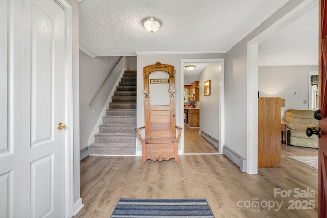 1058 Howard Gap Loop Rd, Flat Rock, NC 28731 - entrance foyer featuring baseboard heating, stairway, a textured ceiling, light wood finished floors, and ornamental molding