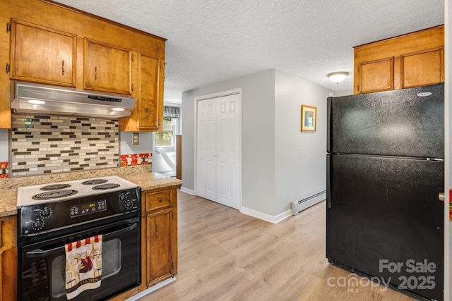 1058 Howard Gap Loop Rd, Flat Rock, NC 28731 - kitchen with black appliances, under cabinet range hood, a baseboard radiator, light wood finished floors, and brown cabinetry