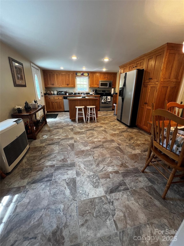 4606 Garvey Bridge Rd, Crumpler, NC 28617 - kitchen with appliances with stainless steel finishes, brown cabinets, recessed lighting, a center island, and stone finish flooring