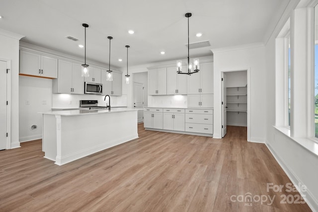 9515 Coast Laurel Ave NW, Concord, NC 28027 - kitchen with stainless steel microwave, light wood-type flooring, light countertops, range with electric cooktop, and a chandelier