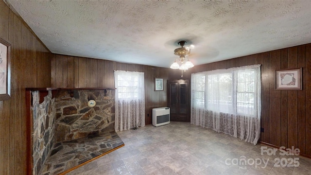 560 Bailey Mountain Rd, Mars Hill, NC 28754 - unfurnished living room featuring healthy amount of natural light, wood walls, heating unit, and a textured ceiling