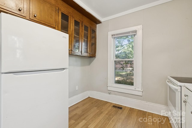 709 E Front St, Statesville, NC 28677 - kitchen featuring white appliances, light wood-type flooring, glass insert cabinets, and brown cabinetry