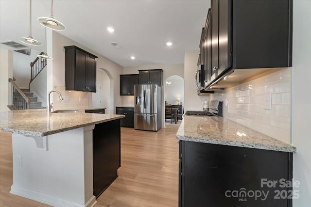 2309 Abundance Ln, Waxhaw, NC 28173 - kitchen with arched walkways, appliances with stainless steel finishes, a peninsula, light stone countertops, and recessed lighting