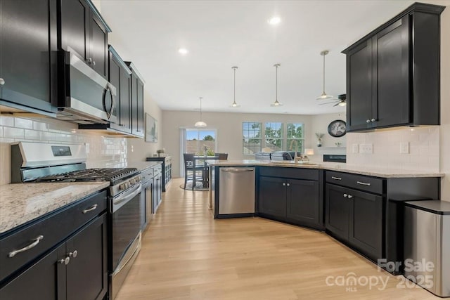 2309 Abundance Ln, Waxhaw, NC 28173 - kitchen featuring stainless steel appliances, light wood-type flooring, a peninsula, backsplash, and light stone countertops
