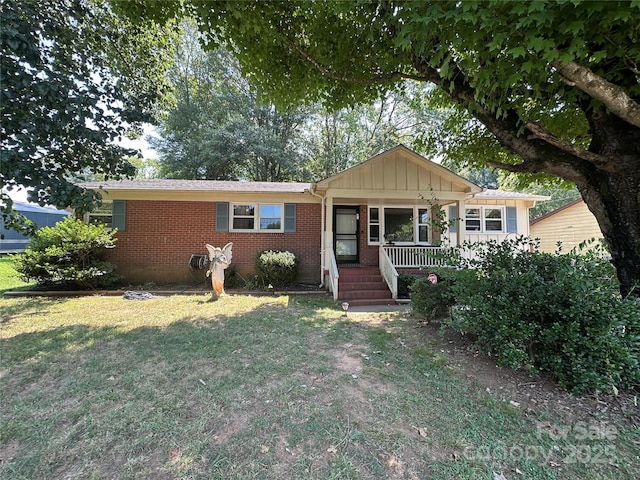 801 Tryon St, Shelby, NC 28150 - view of front of home with covered porch, brick siding, a front lawn, and board and batten siding