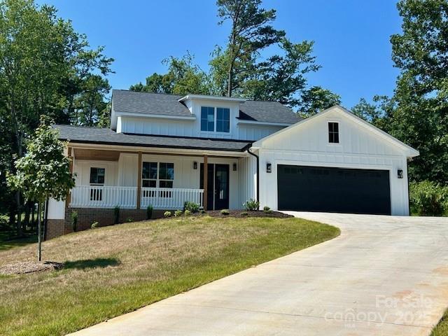141 Maplewood Ct, Hudson, NC 28638 - modern farmhouse featuring board and batten siding, covered porch, driveway, a front lawn, and a garage