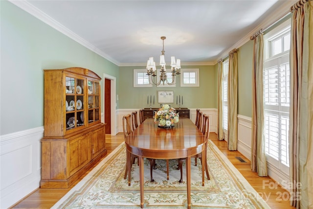 5604 Yorke St NW, Concord, NC 28027 - dining space with a chandelier, wainscoting, light wood-style floors, crown molding, and a decorative wall