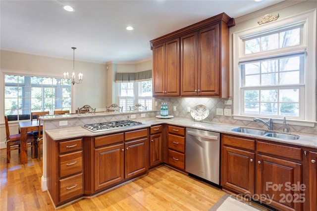 5604 Yorke St NW, Concord, NC 28027 - kitchen featuring stainless steel appliances, a peninsula, light wood-style flooring, a chandelier, and ornamental molding