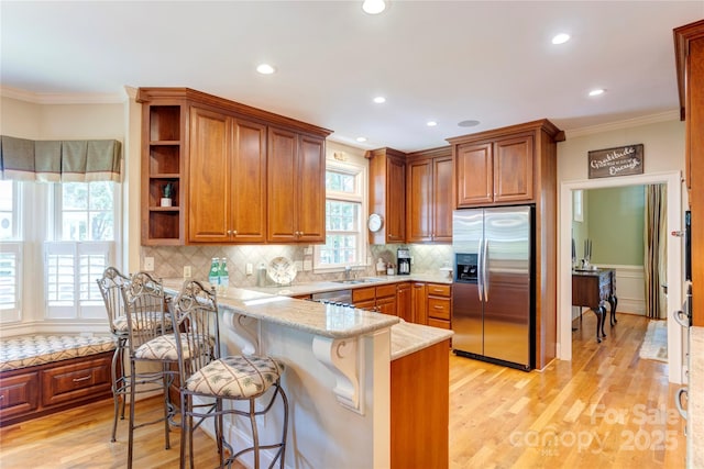 5604 Yorke St NW, Concord, NC 28027 - kitchen with stainless steel appliances, crown molding, a peninsula, brown cabinets, and light wood-style floors