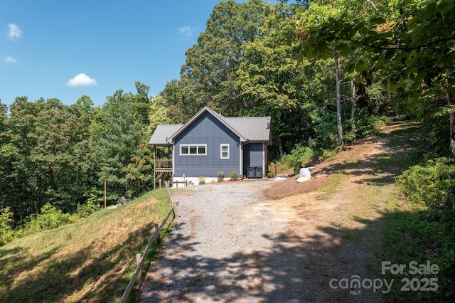 54 Weldon Way, Fairview, NC 28730 - view of front facade with gravel driveway, a metal roof, board and batten siding, and a view of trees