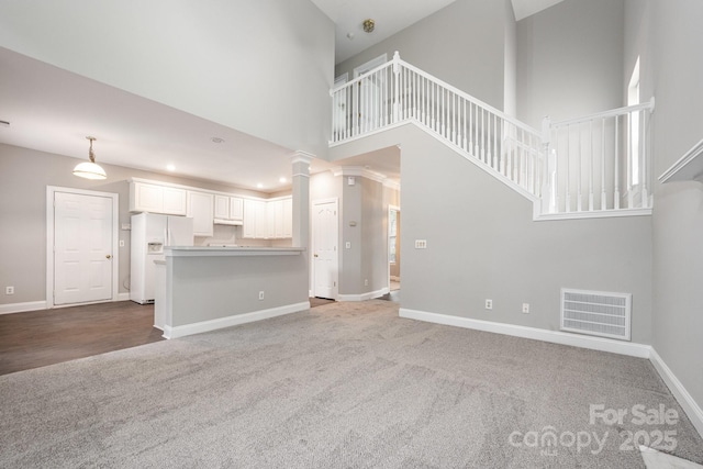 6721 Charter Hills Rd, Charlotte, NC 28277 - unfurnished living room with carpet flooring, ornate columns, a towering ceiling, and stairs