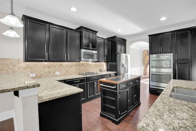 12515 Hashanli Pl, Matthews, NC 28105 - kitchen with stainless steel appliances, dark cabinets, arched walkways, pendant lighting, and decorative backsplash