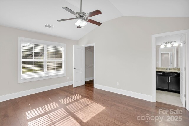 12515 Hashanli Pl, Matthews, NC 28105 - unfurnished bedroom with vaulted ceiling, wood finished floors, a walk in closet, ensuite bath, and a ceiling fan