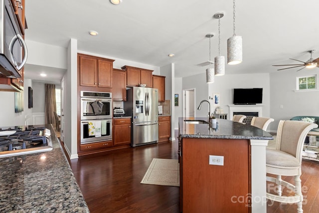 2005 Brightflower Ln, York, SC 29745 - kitchen featuring stainless steel appliances, brown cabinetry, dark wood-type flooring, open floor plan, and a ceiling fan