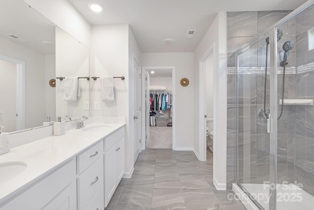 3013 Whipcord Dr, Waxhaw, NC 28173 - full bathroom featuring marble finish floors, double vanity, a shower stall, a walk in closet, and recessed lighting