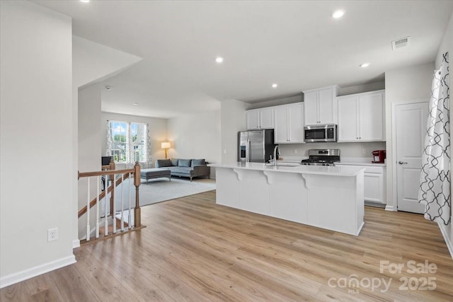 512 Whitehall Cir, Durham, NC 27713 - kitchen featuring appliances with stainless steel finishes, open floor plan, light wood-style floors, white cabinets, and a breakfast bar area