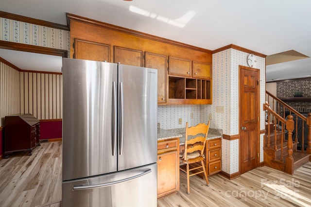 14409 Hackamore Dr, Matthews, NC 28105 - kitchen with wallpapered walls, freestanding refrigerator, light wood-style floors, brown cabinets, and crown molding
