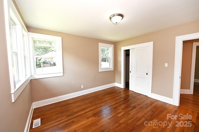 737 8th St SW, Hickory, NC 28602 - unfurnished bedroom featuring multiple windows, wood finished floors, and a closet