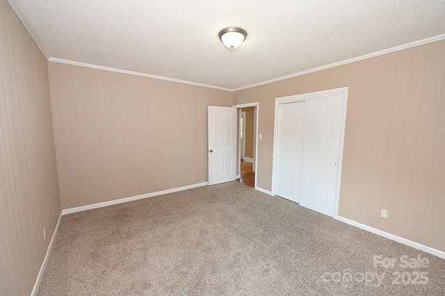 737 8th St SW, Hickory, NC 28602 - unfurnished bedroom with a textured ceiling, carpet floors, a closet, ornamental molding, and wooden walls