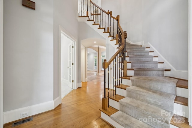 18802 Pentwater Ct, Cornelius, NC 28031 - stairway featuring arched walkways, wood finished floors, and a towering ceiling
