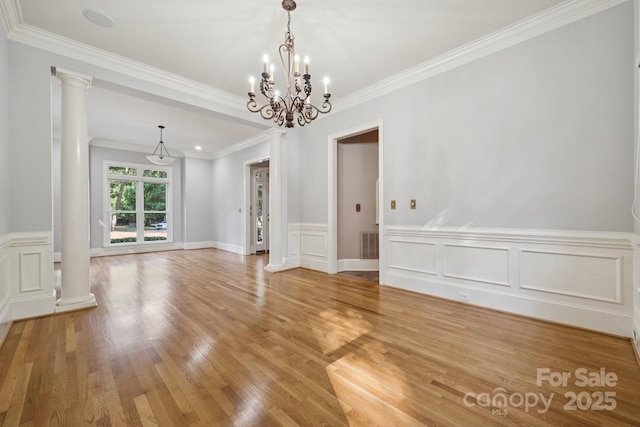 18802 Pentwater Ct, Cornelius, NC 28031 - unfurnished dining area featuring ornate columns, light wood finished floors, crown molding, a wainscoted wall, and a chandelier