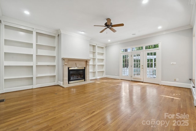 18802 Pentwater Ct, Cornelius, NC 28031 - unfurnished living room with ceiling fan, ornamental molding, built in shelves, light wood-style floors, and a glass covered fireplace