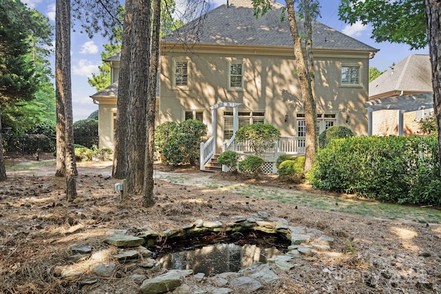 18802 Pentwater Ct, Cornelius, NC 28031 - rear view of house with stucco siding, a wooden deck, a shingled roof, and a garden pond